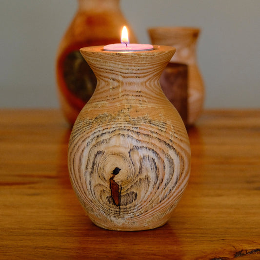 Wooden candle holder with a lit candle on a wooden surface
